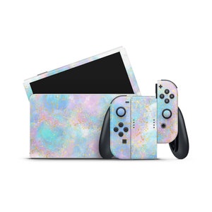 Könnte beinhalten: Eine Nintendo Switch Konsole und zwei Controller mit einem pastellblauen, rosa und goldenen Marmormuster.