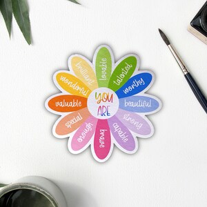 Pu&ograve; includere: Una carta di affermazione colorata a forma di margherita con le parole "You Are" al centro e affermazioni positive intorno ai petali, tra cui "brillante", "amabile", "talentuoso", "degno", "bello", "forte", "capace", "abbastanza", "speciale", "prezioso" e "meraviglioso".