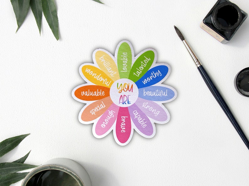 Pu&ograve; includere: Una carta di affermazione colorata a forma di margherita con le parole "You Are" al centro e affermazioni positive intorno ai petali, tra cui "brillante", "amabile", "talentuoso", "degno", "bello", "forte", "capace", "abbastanza", "speciale", "prezioso" e "meraviglioso".