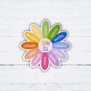 Pu&ograve; includere: Un adesivo colorato a forma di margherita con le parole "You Are" al centro e affermazioni positive intorno ai petali, tra cui "talented", "worthy", "beautiful", "strong", "capable", "enough", "special", "valuable", "wonderful", "brilliant", "lovable".