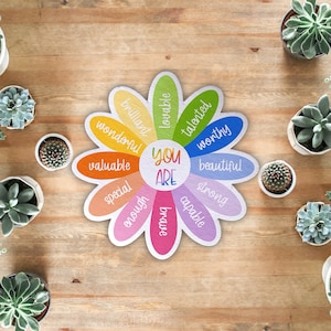 Pu&ograve; includere: Un poster di affermazione a forma di fiore colorato con le parole "You Are" al centro e affermazioni positive intorno ai petali, come "brillante", "amabile", "talentuoso", "degno", "bello", "forte", "capace", "abbastanza", "speciale", "prezioso", "meraviglioso".