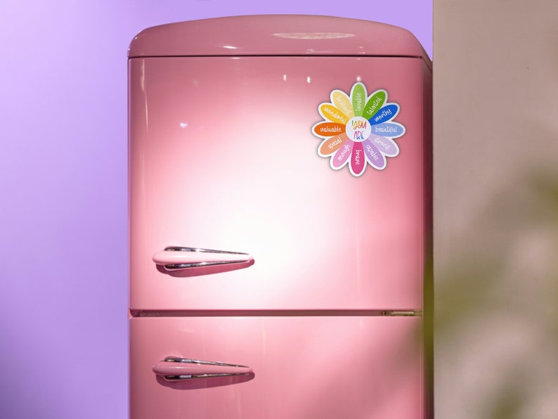 Pu&ograve; includere: Un frigorifero rosa con un magnete a forma di fiore sulla porta. Il magnete ha la parola "YOU" al centro ed &egrave; circondato da parole come "valuable", "special", "unique", "amazing", "beautiful", "kind", "strong", "friendly", "wonderful", "inspiring", e "creative".
