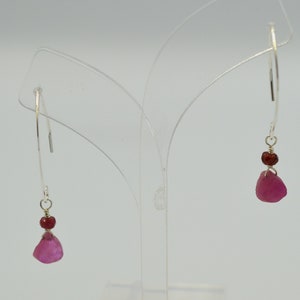May include: A pair of silver dangle earrings with pink and red gemstone accents.