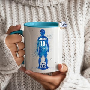 May include: White ceramic mug with a blue rim. The mug features a watercolour illustration of a football player with the name "Jenson" and the number "10" on the back of the jersey.