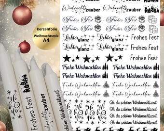 May include: A sheet of white sticker paper with black Christmas-themed designs. The designs include the words "Frohes Fest", "Weihnachtszauber", "Lichterglanz", "Frohe Weihnachten", and "Oh du schöne Weihnachtszeit".