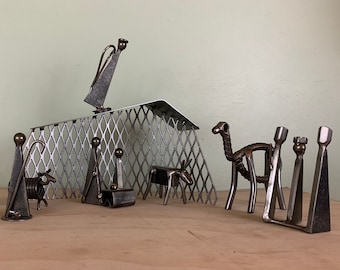 May include: A metal nativity scene with a metal mesh stable, a camel, a shepherd, a sheep, and three wise men.