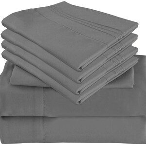 May include: A stack of six gray fitted sheets. The sheets are made of a soft, smooth fabric and are wrinkle-resistant.