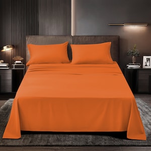 May include: A bright orange bed sheet set with two matching pillowcases. The sheet is smooth and wrinkle-free, and the pillowcases are soft and comfortable.