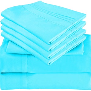 May include: A stack of six light blue bed sheets. The sheets are folded neatly and are made of a soft, smooth fabric.