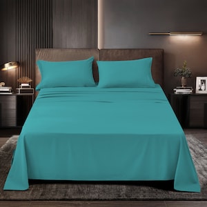 May include: A teal blue bed sheet set with two matching pillowcases. The bed is made with a dark brown headboard and a teal blue bedspread.