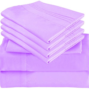 May include: A stack of six lavender-colored bed sheets. The sheets are folded neatly and have a smooth, silky texture.