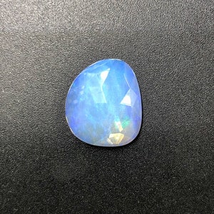 May include: A light blue, faceted, teardrop-shaped gemstone with iridescent flashes of color.