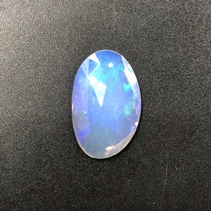 May include: A light blue oval opal gemstone with iridescent flashes of color.