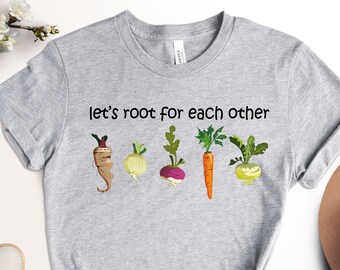 May include: Gray t-shirt with the text "Let's root for each other" and a row of five cartoon vegetables: a parsnip, an onion, a turnip, a carrot, and a kohlrabi.