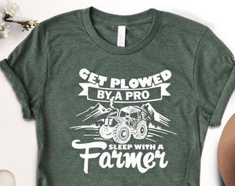 May include: Green t-shirt with white text that reads "Get Plowed By A Pro" with a tractor graphic and "Sleep With A Farmer".