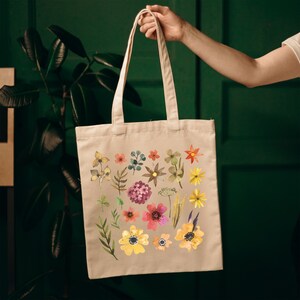 May include: A beige canvas tote bag with a floral print featuring a variety of flowers in shades of yellow, orange, pink, and red. The flowers are arranged in a random pattern on the bag.