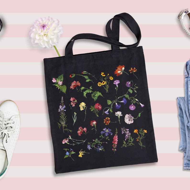 Peut inclure: Un sac fourre-tout noir avec un imprim&eacute; floral pr&eacute;sentant une vari&eacute;t&eacute; de fleurs color&eacute;es, notamment roses, violettes, jaunes et rouges.