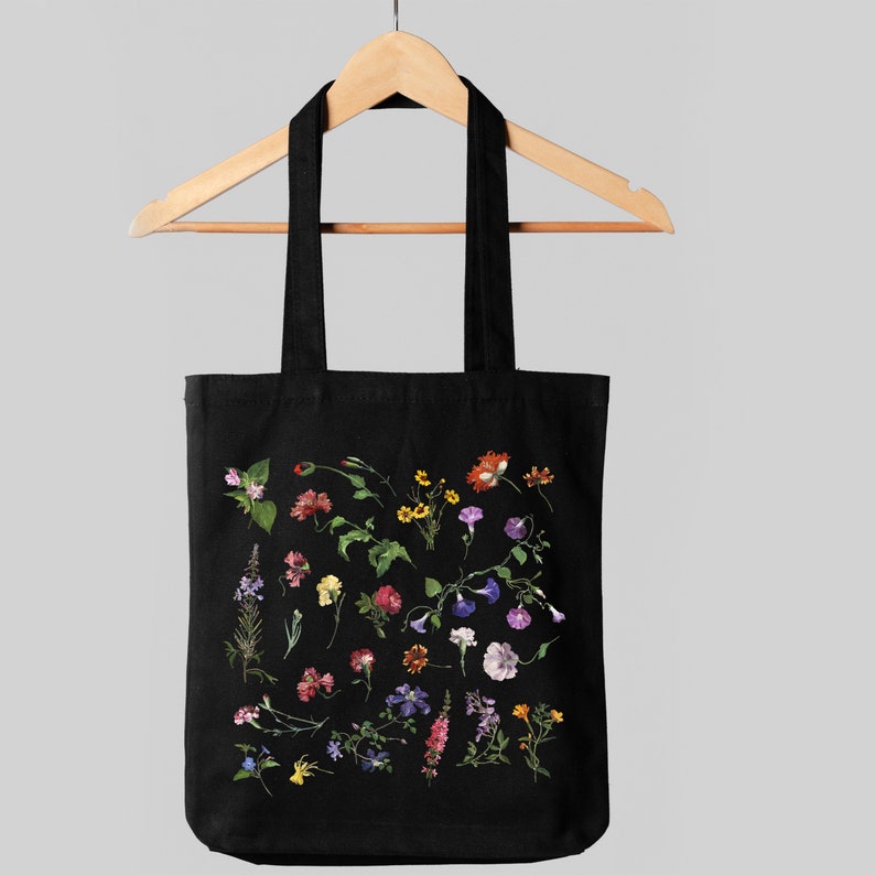 Peut inclure: Sac fourre-tout noir avec un imprim&eacute; floral pr&eacute;sentant une vari&eacute;t&eacute; de fleurs color&eacute;es, notamment roses, violettes, jaunes, oranges et rouges.