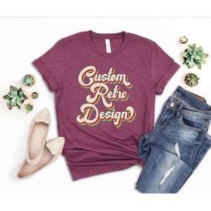 May include: A maroon t-shirt with the text "Custom Retro Design" in a retro font with rainbow colors.