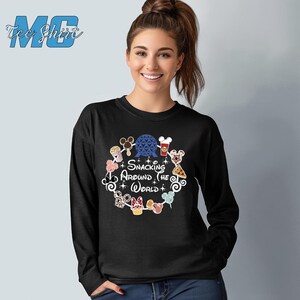 May include: Black long-sleeve shirt with a graphic of a circle of Disney characters and food items. The text "Snacking Around the World" is in the center of the circle.