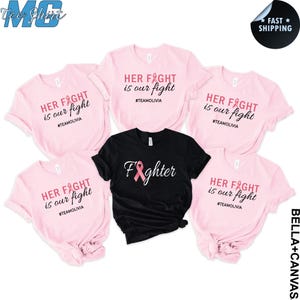 May include: Pink and black t-shirts with breast cancer awareness themes. The pink shirts read "HER FIGHT is our fight" with a pink ribbon graphic and the hashtag #TEAMOLIVIA. The black shirt says "Fighter" with a pink ribbon.