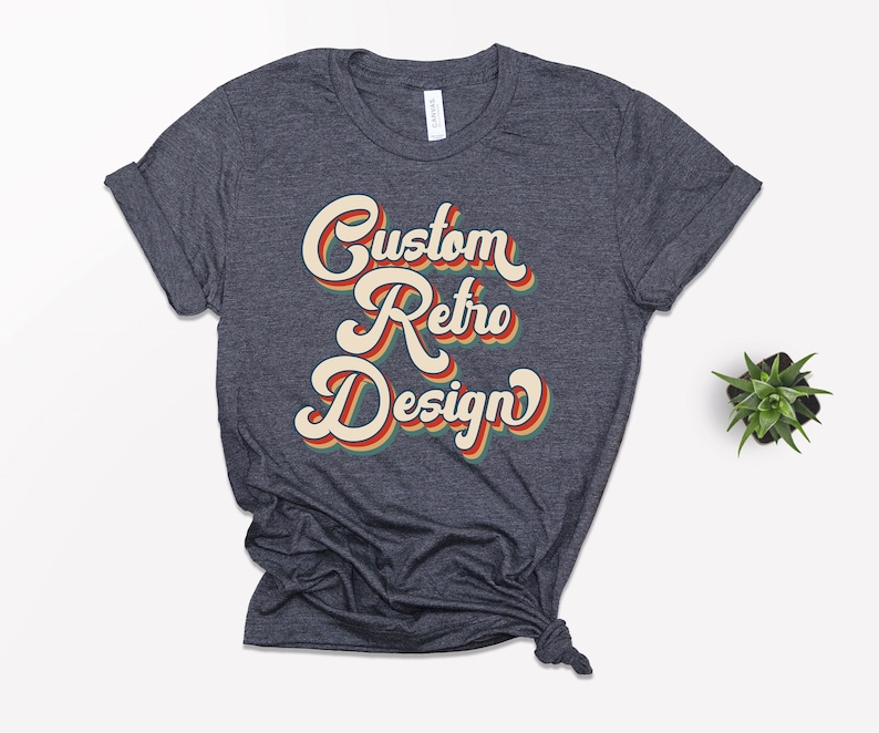 May include: A dark heather grey t-shirt with a retro-style graphic that says "Custom Retro Design" in orange, yellow, and green.