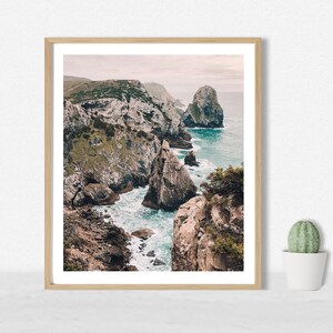 May include: A framed photograph of a rocky coastline with turquoise water crashing against the rocks. The photo is taken from a high vantage point, looking down at the water.