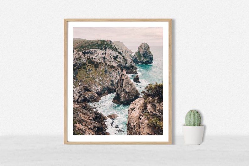 May include: A framed photograph of a rocky coastline with turquoise water crashing against the rocks. The photo is taken from a high vantage point, looking down at the water.