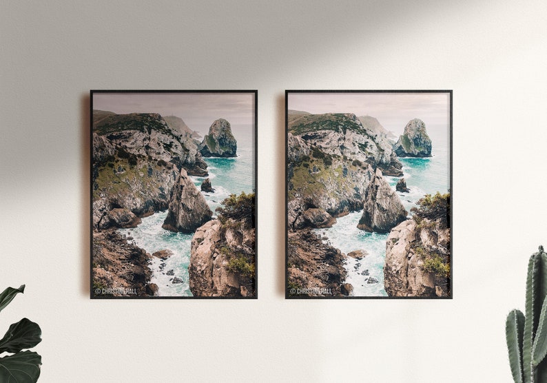 May include: Two framed photographs of a rocky coastline with turquoise water crashing against the rocks. The photos are hung on a white wall.