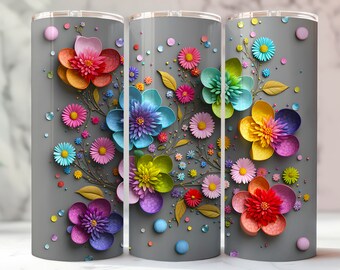 May include: Three gray stainless steel tumblers with a colorful floral design. The flowers are made of paper and are layered in different colors, including pink, yellow, blue, green, and red. The flowers are arranged in a bouquet-like pattern on the tumblers.