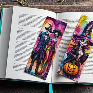 Puede incluir: Dos marcadores de libros con tem&aacute;tica de Halloween. Uno presenta una pareja con trajes coloridos, el otro una bruja sosteniendo una calabaza. Ambos marcadores est&aacute;n pintados en estilo acuarela.