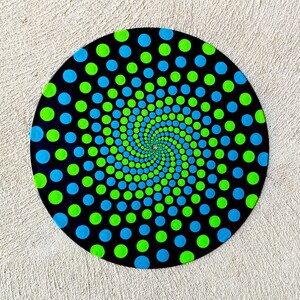 May include: A black circular vinyl record with a swirling pattern of green and blue dots on a black background.