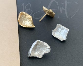 May include: A pair of earrings with a textured, irregular shape. One earring is gold and the other is silver.