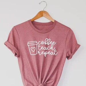 May include: A pink t-shirt with a white coffee cup graphic and the text "coffee teach repeat".