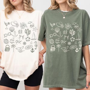 Two women wearing t-shirts with various beach and ocean-themed illustrations printed on them.