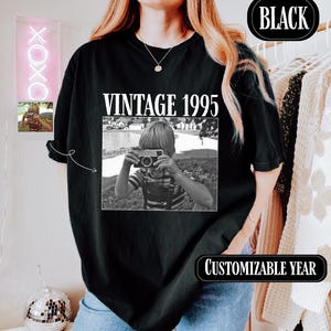 a woman wearing a black shirt with a picture of a woman holding a camera