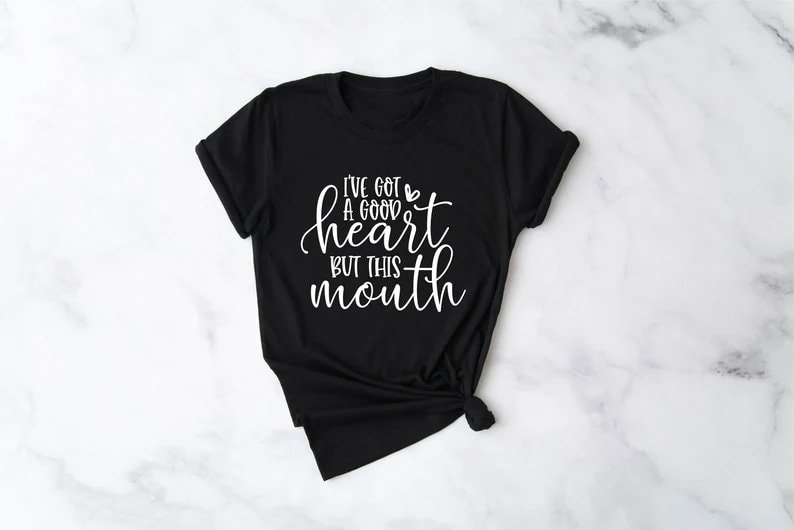 May include: Black t-shirt with a white graphic that says "I've got a good heart but this mouth".