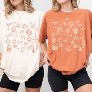Two women wearing t-shirts with various beach and ocean-themed illustrations.