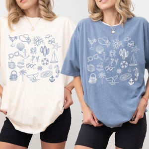 Two women wearing t-shirts with various beach and nautical-themed illustrations.