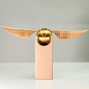 Propuesta de matrimonio: Snitch dorada con compartimento para anillos en un soporte impreso en 3D. Propuesta de compromiso.