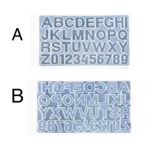 May include: Two clear silicone molds for making letters and numbers. The top mold shows the letters A through I and the numbers 0 through 9 in a single row. The bottom mold shows the letters J through Z and the numbers 0 through 9 in a single row.