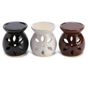 May include: Three ceramic essential oil diffusers in black, white, and brown. Each diffuser has a round top and a flower-shaped cutout design.