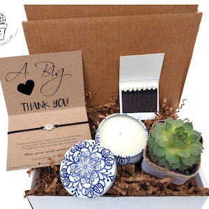 May include: A gift box filled with a succulent plant, a candle, matches, and a card that says "A Big Thank You!" with a wish bracelet.