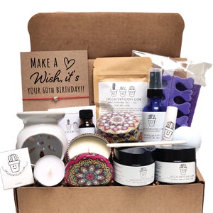 May include: A brown cardboard box filled with a variety of self-care items, including a candle, bath salts, body scrub, and essential oil. The box also includes a card that says "Make a Wish, it's your 60th Birthday!!".