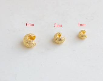 May include: Three gold-colored crimp beads in varying sizes: 6mm, 5mm, and 4mm. Each bead has a textured surface and a C-shape design, ideal for jewelry making. The beads are displayed against a plain white background.