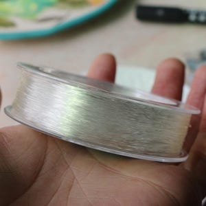 May include: A spool of clear fishing line in a plastic container.