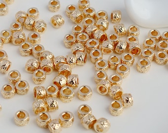 Peut inclure: Un grand nombre de perles en métal de couleur dorée avec une surface texturée. Les perles sont rondes et ont un trou au centre.
