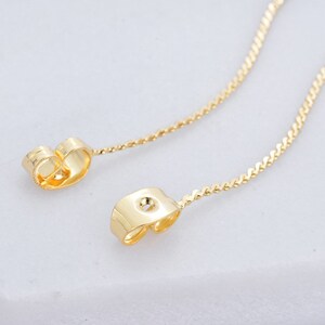 Puede incluir: Un par de extensores de pendientes de color dorado con un diseño de cadena delicado. Los extensores están hechos de metal y tienen un cierre seguro.