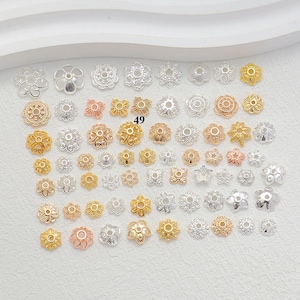May include: A collection of assorted metal bead caps in various floral and geometric shapes, finished in gold, silver, and rose gold tones. The pieces are arranged in a grid pattern, with the number 49 printed in black near the centre.