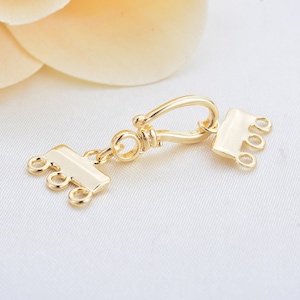 May include: Gold-tone metal clasp with a hook and three loops on each side. The clasp is designed for attaching to jewelry chains or necklaces.